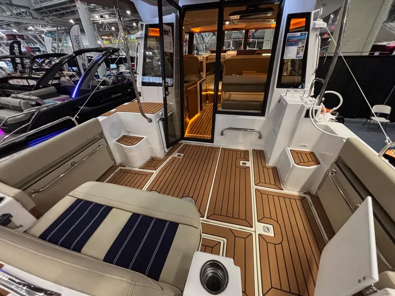 Slide: The Image of 2025 Ranger Tugs R-29 S interior with teak flooring and seating at a boat show. - 4