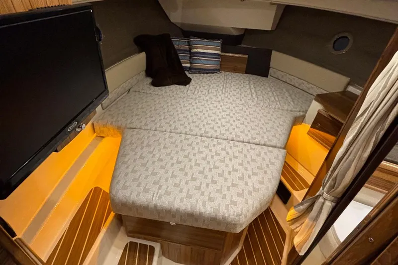 Slide: The Image of 2025 Ranger Tugs R-29 S interior cabin with cozy bed, ambient lighting, and TV. - 8