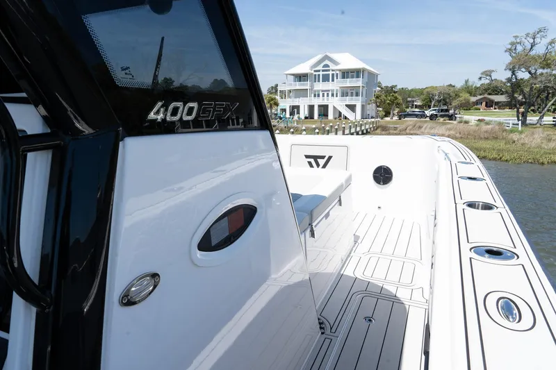Slide: The Image of 2025 Twin Vee 400 GFX2 CC boat docked near a waterfront house, showcasing sleek design. - 21