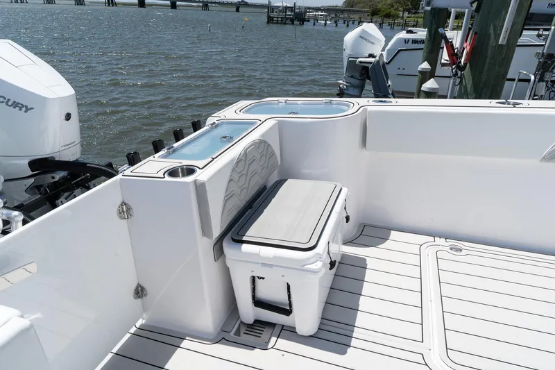 Slide: The Image of 2025 Twin Vee 400 GFX2 CC boat deck with seating and storage, docked by the water. - 3