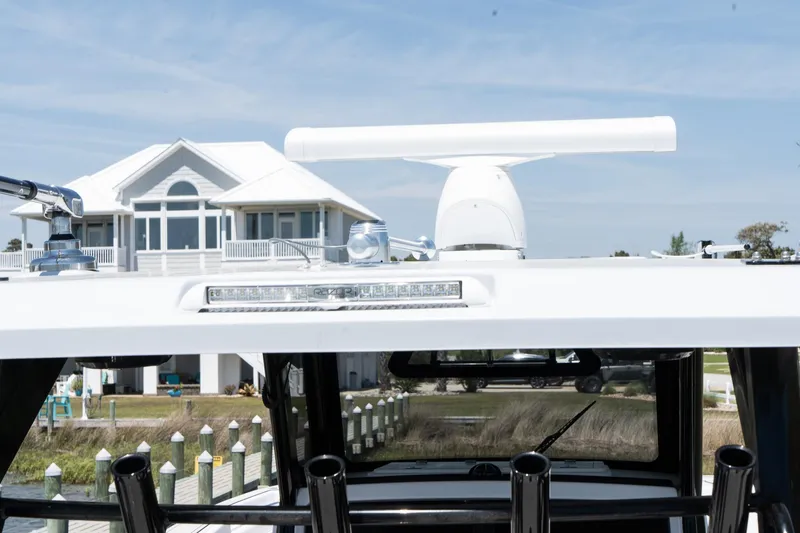 Slide: The Image of 2025 Twin Vee 400 GFX2 CC boat with radar, docked near a waterfront house. - 47