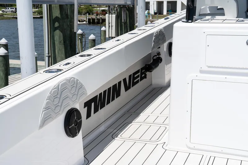 Slide: The Image of 2025 Twin Vee 400 GFX2 CC boat deck with logo, docked by the water. - 5