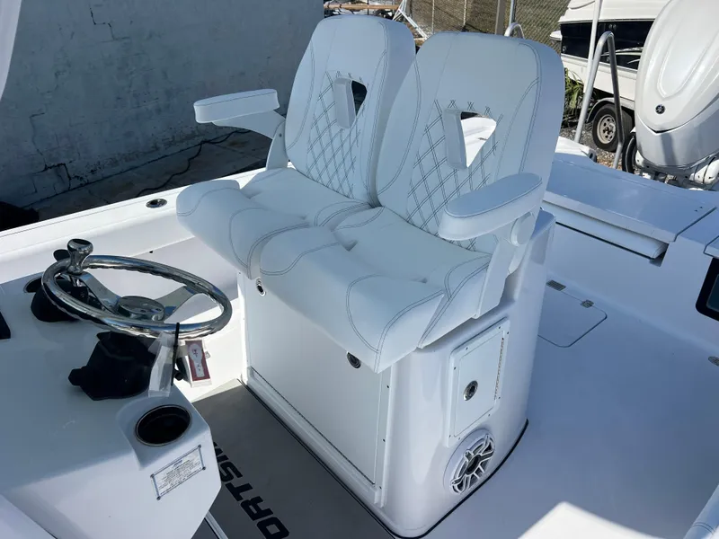 Slide: The Image of 2025 Sportsman Masters 267OE Bay Boat cockpit with dual white cushioned seats and steering wheel. - 16