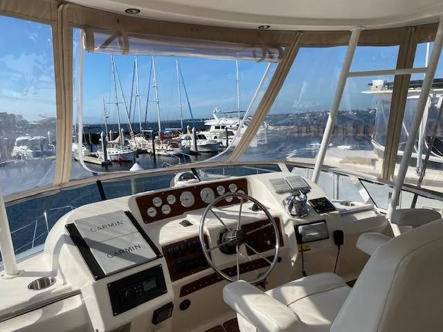 Slide: The Image of Interior view of 2002 Silverton 453 Motor Yacht helm with marina background. - 11