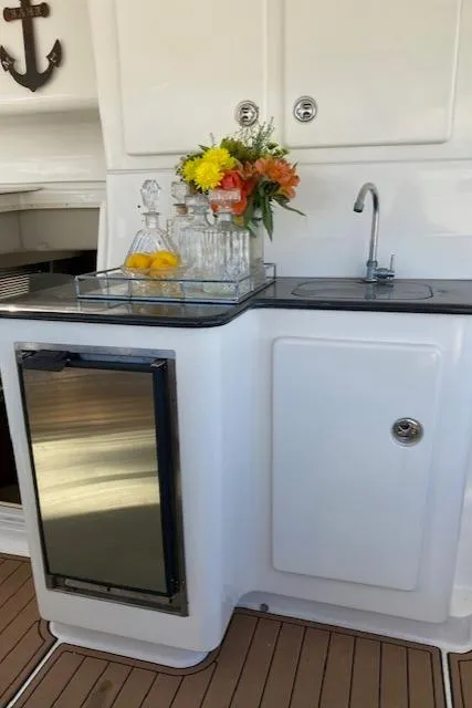 Slide: The Image of 2002 Silverton 453 Motor Yacht kitchenette with sink, mini fridge, and floral arrangement. - 19