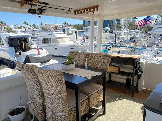 Slide: The Image of 2002 Silverton 453 Motor Yacht deck with dining area, marina view, and wicker chairs. - 7
