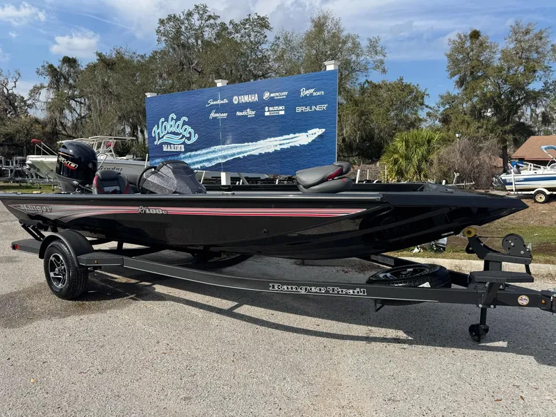 The Image of 2025 Ranger RT188C boat on trailer, parked outdoors with promotional sign in background. - 0