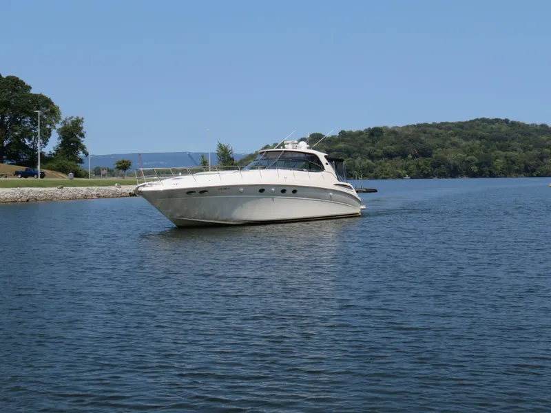 The Image of 2001 Sea Ray 510DA yacht cruising on a serene lake with lush green hills. - 0
