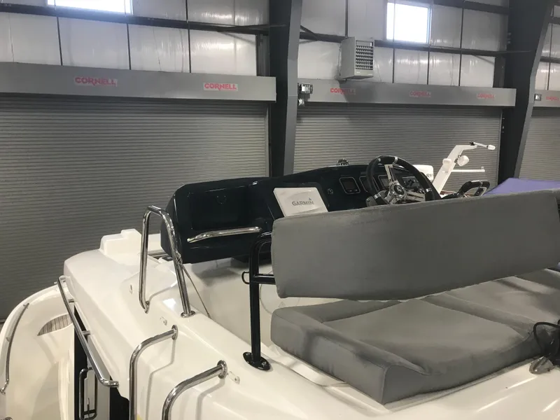 Slide: The Image of 2013 Beneteau Barracuda 9 boat interior with seating and control panel in a garage. - 24