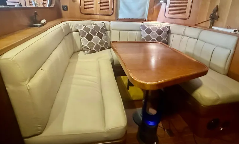 Slide: The Image of Cozy dining area in 1999 Passport Royal 43 yacht with cushioned seating and wooden table. - 12