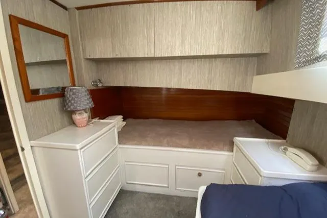 Slide: The Image of 1971 Matthews Motor Yacht cabin with bed, wooden paneling, dresser, and lamp. - 46