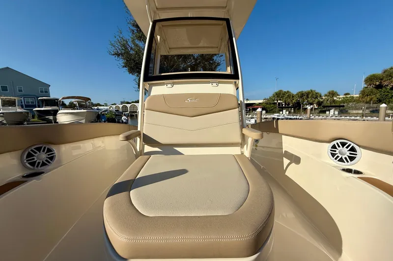 Slide: The Image of 2025 Scout 215 XSF boat interior with beige seating and speakers, docked under clear blue sky. - 14