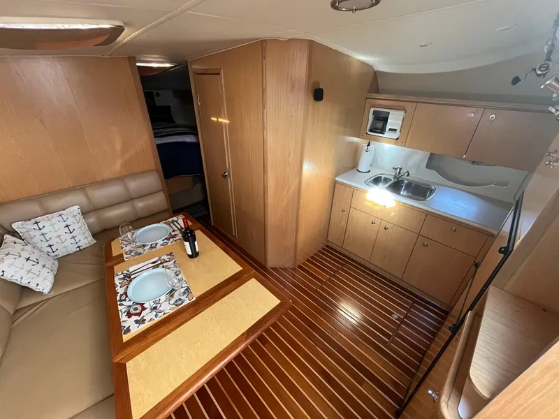 Slide: The Image of Interior of 2001 Tiara Yachts 4100 Open, featuring kitchen and dining area with wooden flooring. - 23