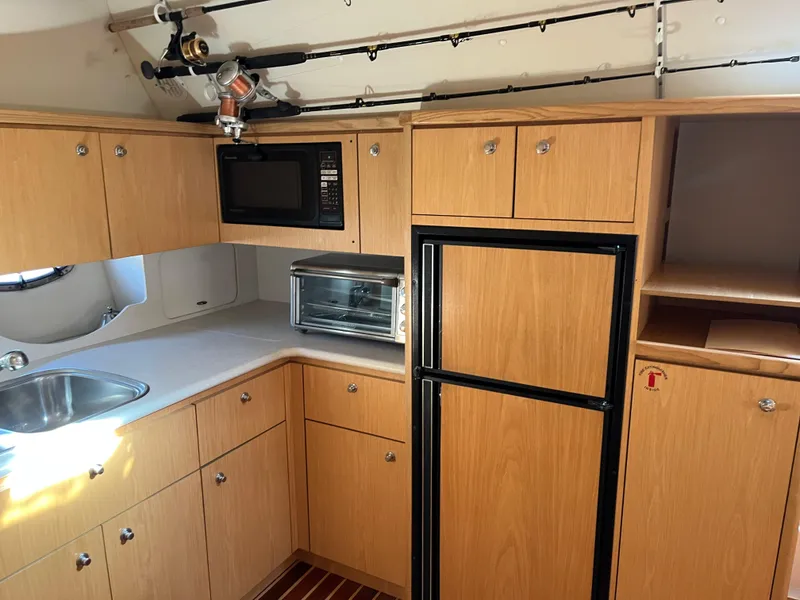 Slide: The Image of 2001 Tiara Yachts 4100 Open kitchen with wood cabinets, sink, microwave, and fridge. - 29