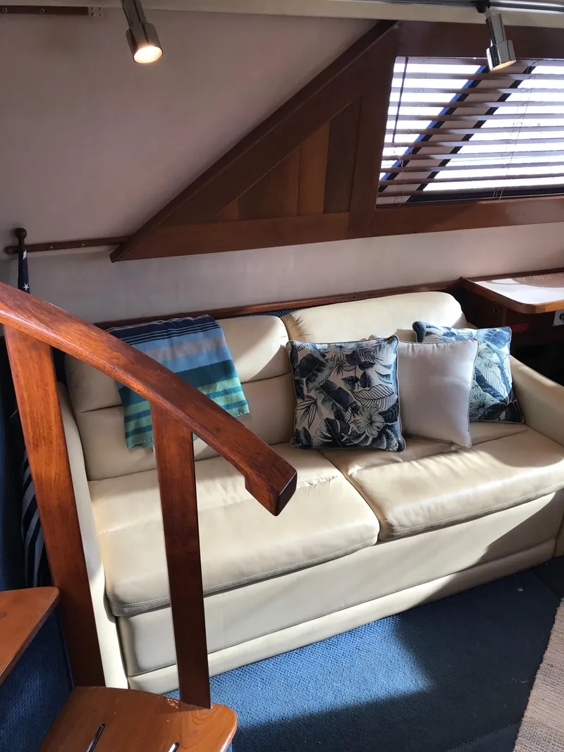 Slide: The Image of 1987 Sea Ray 410 Aft Cabin interior with beige sofa, decorative pillows, and wooden accents. - 52