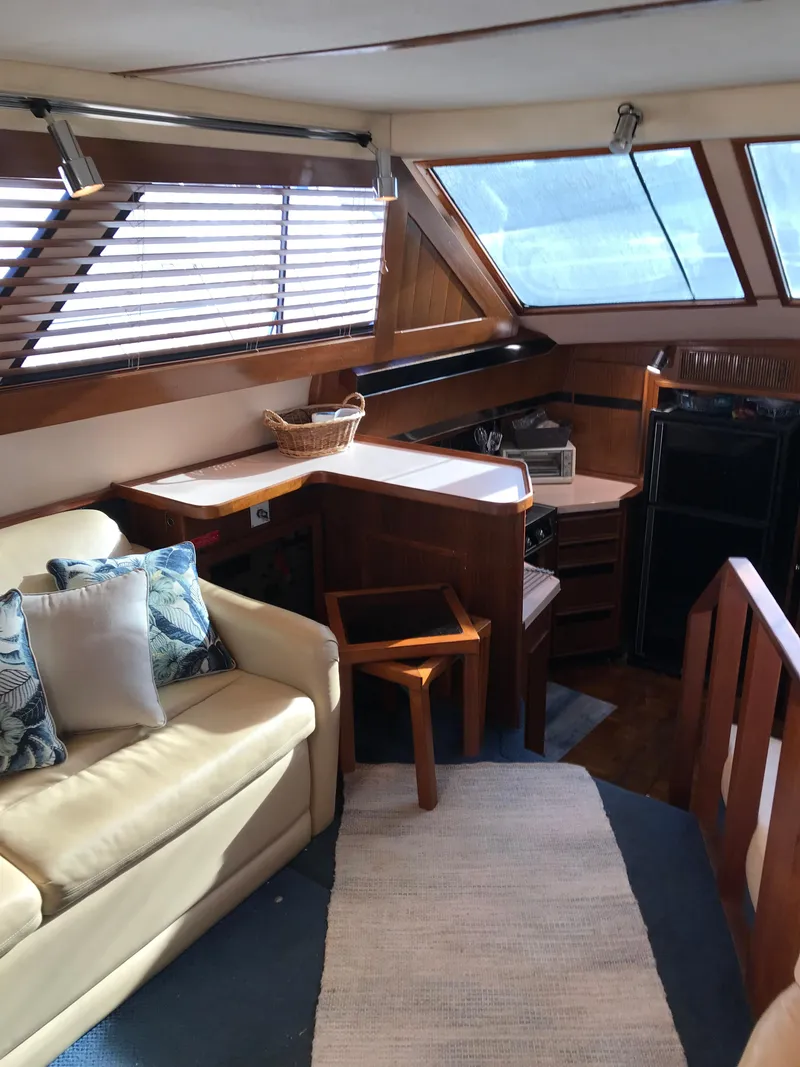 Slide: The Image of 1987 Sea Ray 410 Aft Cabin interior with sofa, wooden accents, and large windows. - 53
