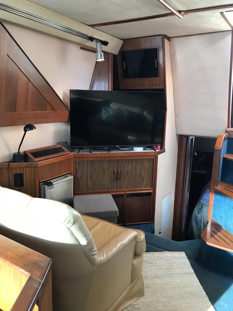 Slide: The Image of 1987 Sea Ray 410 Aft Cabin interior with TV, chair, and wooden cabinetry. - 57