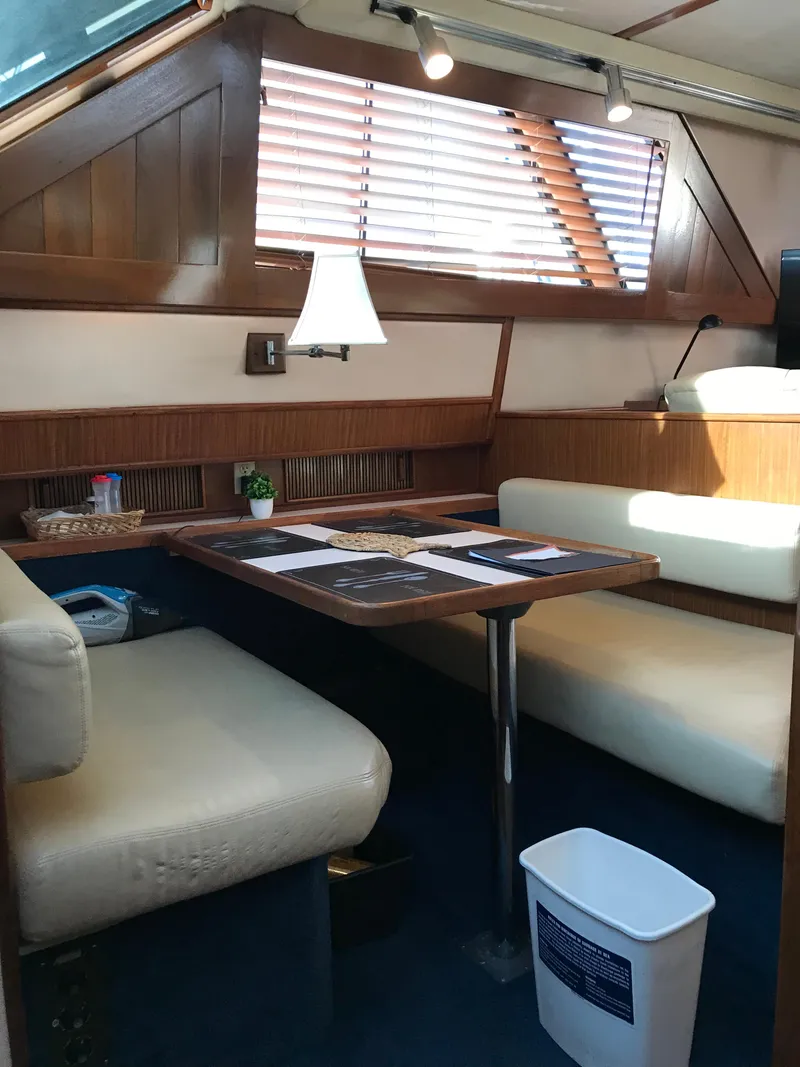 Slide: The Image of 1987 Sea Ray 410 Aft Cabin interior with dining area, wooden accents, and natural light. - 58