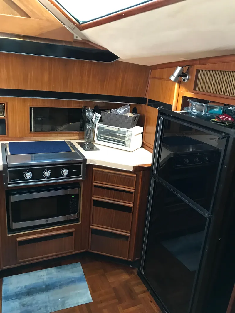 Slide: The Image of 1987 Sea Ray 410 Aft Cabin kitchen with stove, fridge, and wood cabinetry. - 60