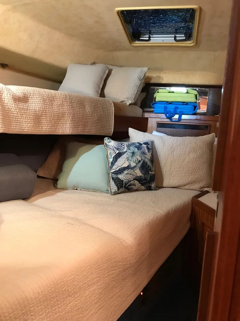 Slide: The Image of 1987 Sea Ray 410 Aft Cabin interior with cozy bedding and decorative pillows. - 64