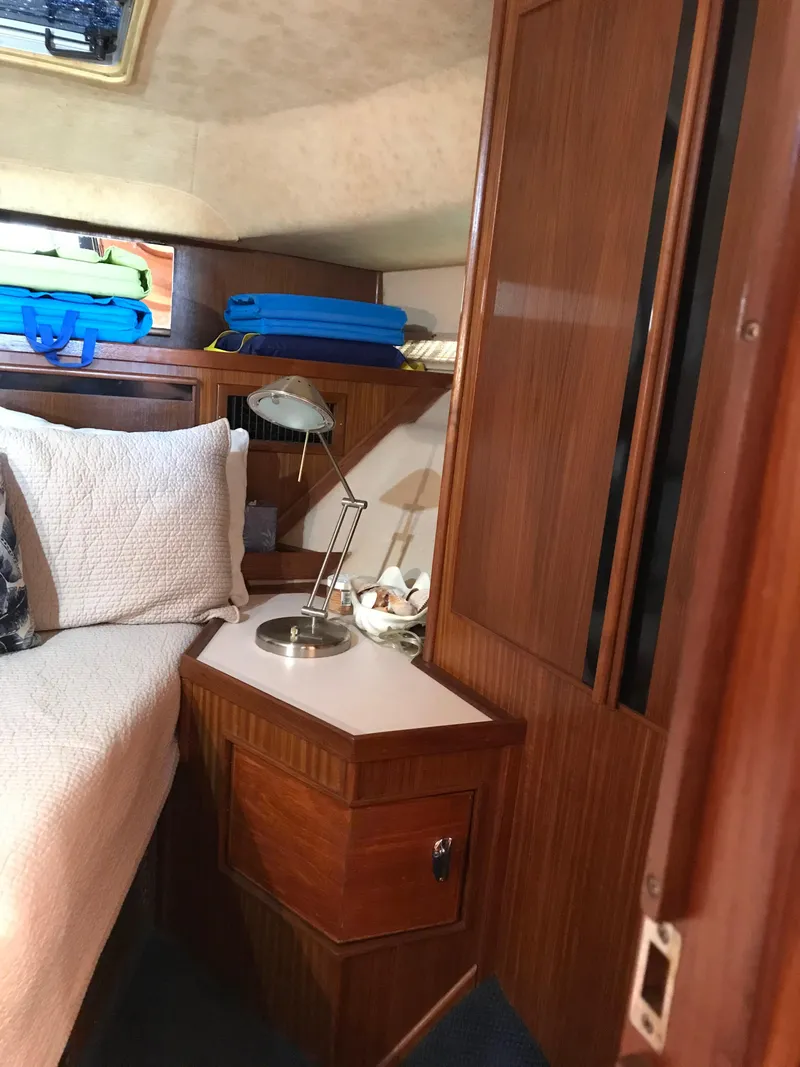 Slide: The Image of 1987 Sea Ray 410 Aft Cabin interior with wood paneling and cozy bed setup. - 66