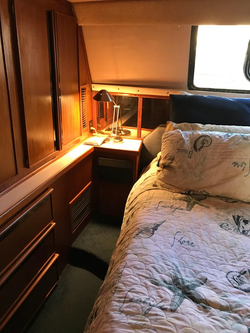 Slide: The Image of 1987 Sea Ray 410 Aft Cabin bedroom with wood cabinetry and nautical-themed bedding. - 72