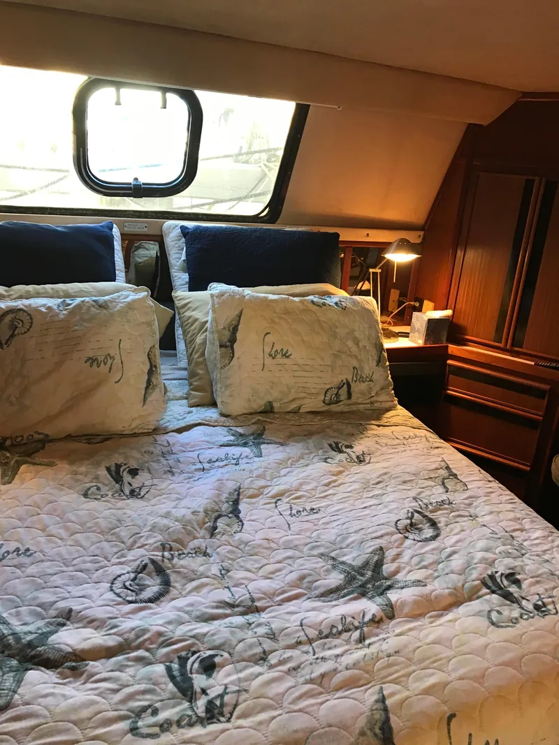 Slide: The Image of 1987 Sea Ray 410 Aft Cabin bedroom with nautical-themed bedding and cozy lighting. - 73