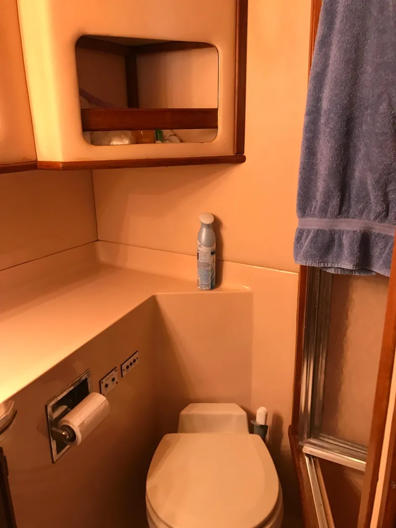 Slide: The Image of 1987 Sea Ray 410 Aft Cabin bathroom with toilet, towel, and storage shelf. - 78
