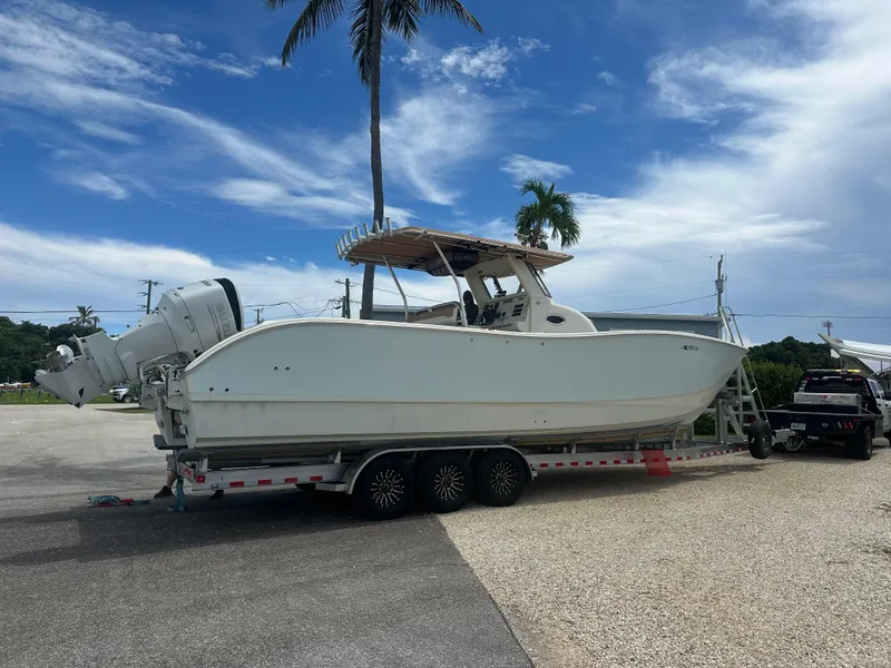 Slide: The Image of 2009 Mamba 350 boat on trailer, parked outdoors under a clear blue sky. - 2