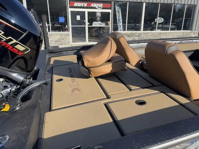 Slide: The Image of 2025 Xpress H18 boat with tan seating and storage compartments, displayed at a marine dealership. - 4