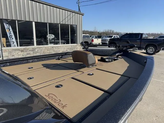 Slide: The Image of 2025 Xpress H18 boat with tan SeaDek flooring, parked outside a showroom. - 7