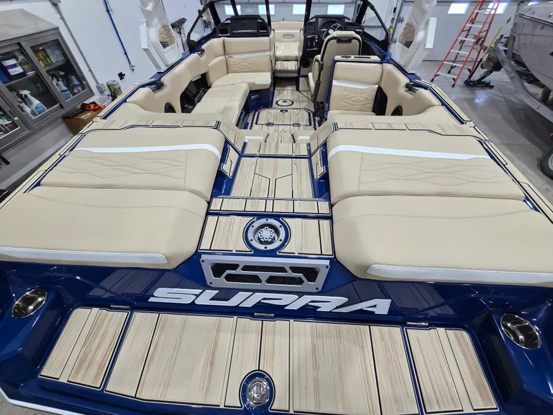 Slide: The Image of 2025 Supra SV boat interior with beige seating and blue accents in a showroom. - 14
