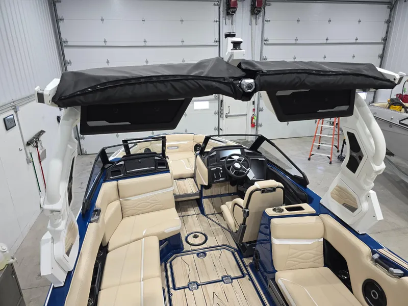 Slide: The Image of 2025 Supra SV boat interior with beige seating and modern dashboard in a garage setting. - 16