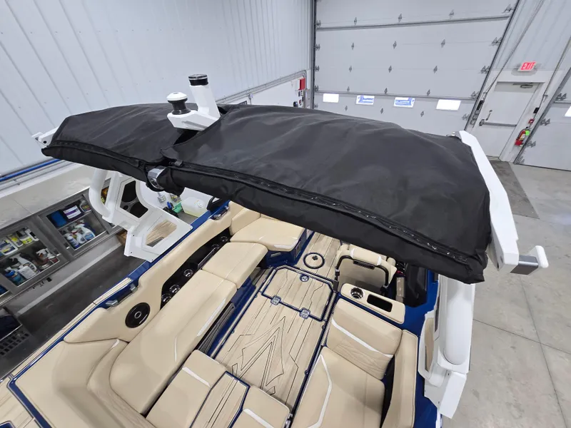 Slide: The Image of 2025 Supra SV boat interior with beige seating and black canopy in a garage setting. - 18