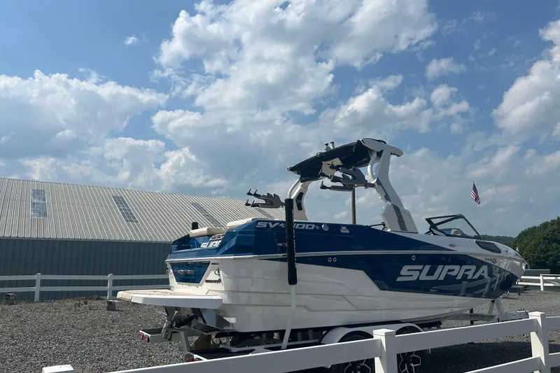 Slide: The Image of 2025 Supra SV boat on trailer, parked outdoors under a partly cloudy sky. - 5