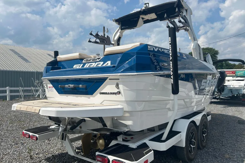 Slide: The Image of 2025 Supra SV boat with blue and white design, parked on a trailer. - 6