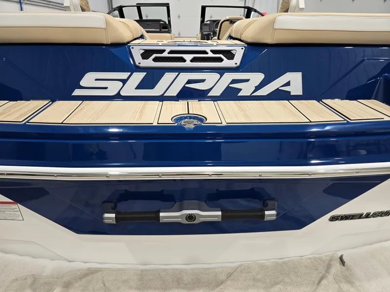 Slide: The Image of 2025 Supra SV boat, blue and white design, rear view with logo and seating. - 9