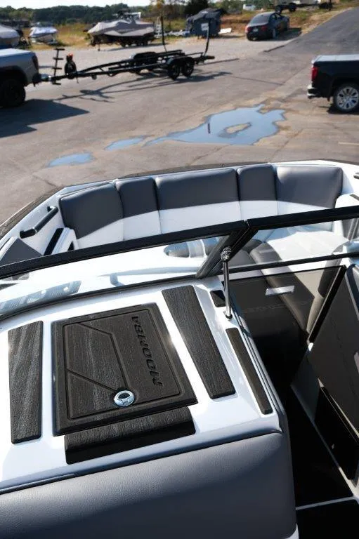 Slide: The Image of 2025 Moomba Max boat interior with seating and dashboard, parked near trailers. - 13