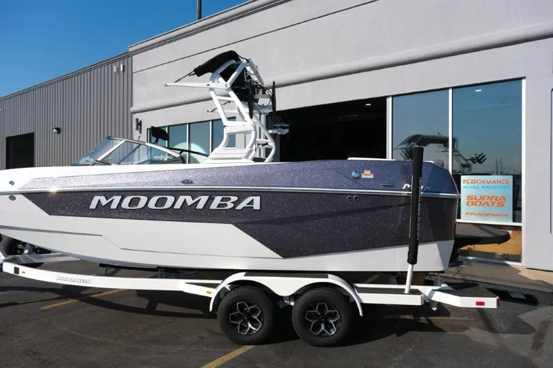 Slide: The Image of 2025 Moomba Max boat on trailer outside dealership. - 2