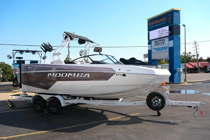 Slide: The Image of 2025 Moomba Max boat on trailer in parking lot, near dealership sign. - 5