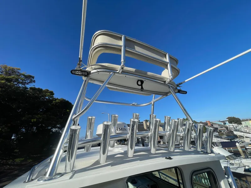 Slide: The Image of 2020 Parker 2320 Sport Cabin boat with rod holders and tower against clear blue sky. - 13