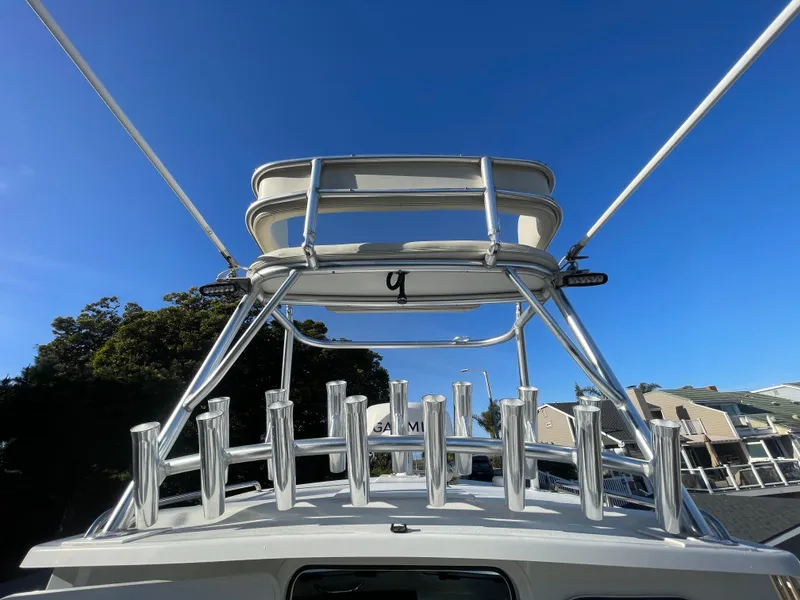 Slide: The Image of 2020 Parker 2320 Sport Cabin boat with rod holders and tower against clear blue sky. - 14
