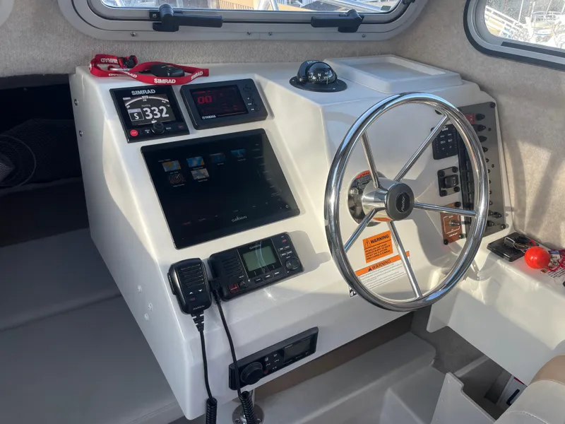 Slide: The Image of 2020 Parker 2320 Sport Cabin helm with steering wheel and navigation instruments. - 23