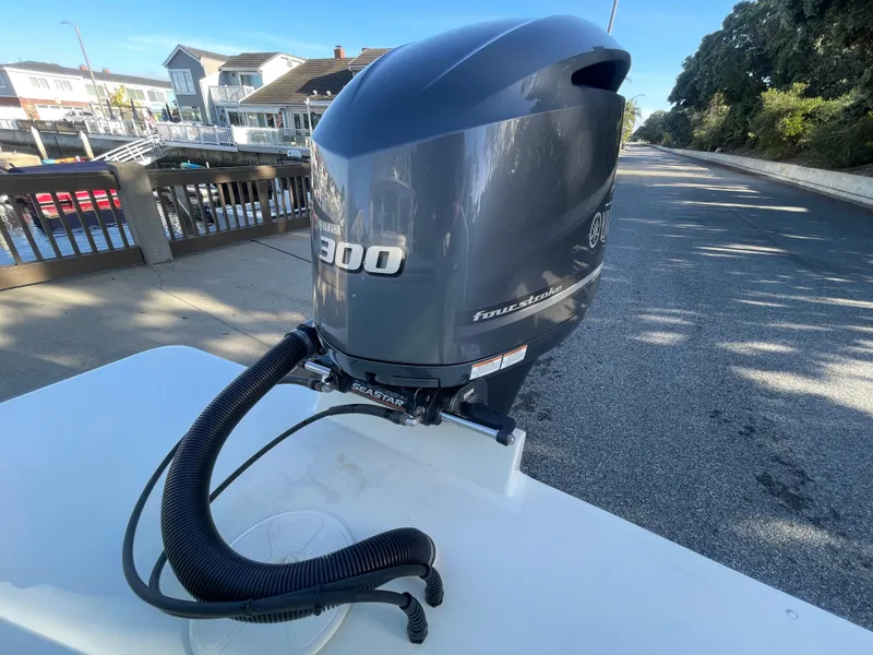 Slide: The Image of Outboard motor on a 2020 Parker 2320 Sport Cabin boat, parked near waterfront homes. - 32