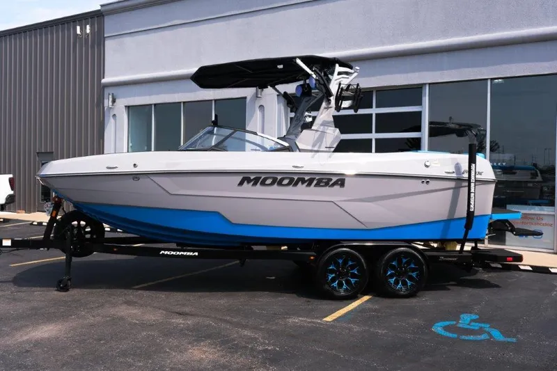 Slide: The Image of 2025 Moomba Max boat on trailer, parked outside a building. - 2