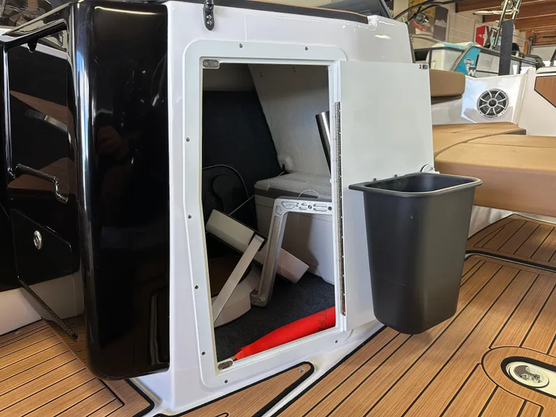 Slide: The Image of 2024 Yamaha 222SD jet boat interior storage compartment with open door and trash bin. - 12