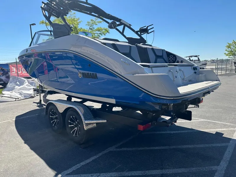 Slide: The Image of 2024 Yamaha 222XD jet boat on trailer, blue and white design, parked outdoors. - 7