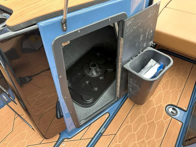 Slide: The Image of 2024 Yamaha 222XD boat storage compartment with trash bin on wooden deck. - 19