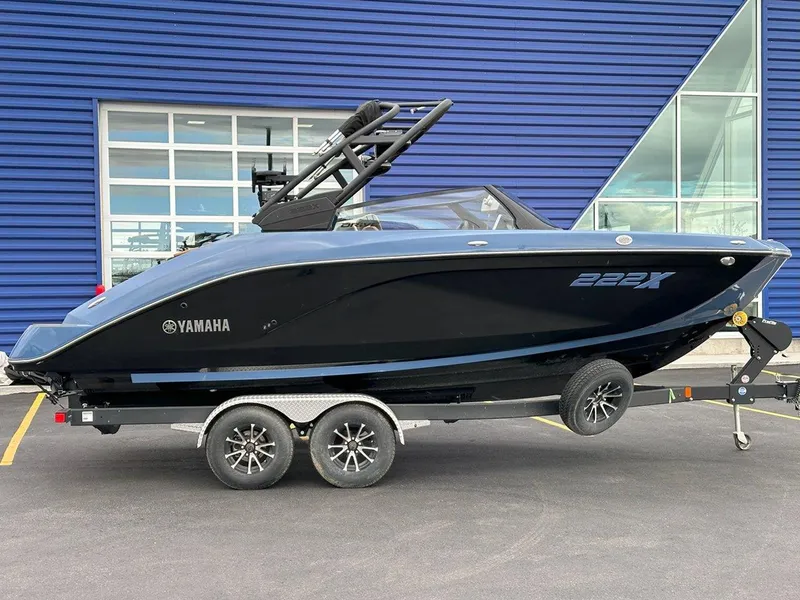 Slide: The Image of 2024 Yamaha 222XD jet boat on trailer, parked outside a blue building. - 2