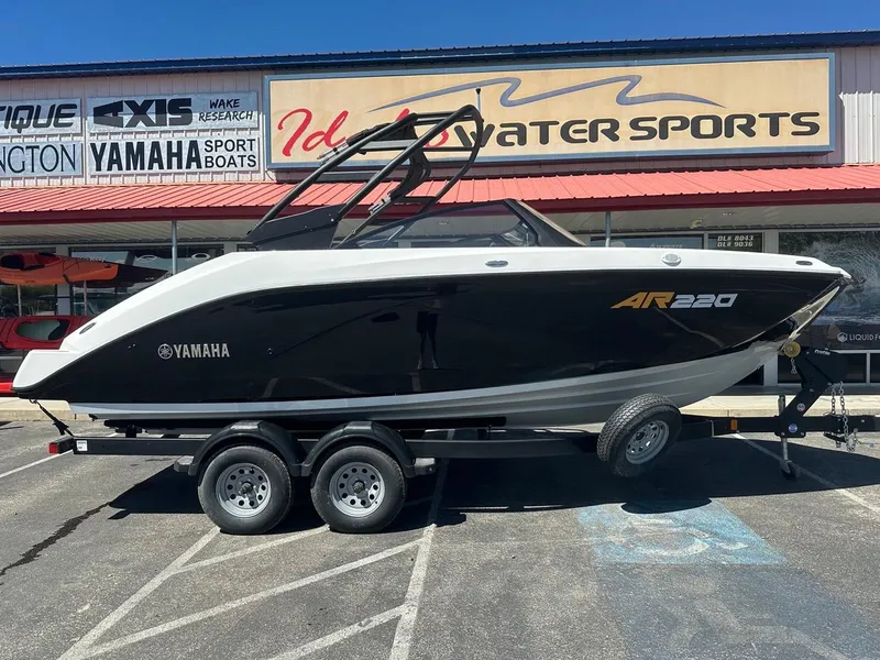Slide: The Image of Sleek 2024 Yamaha AR220 boat on trailer, parked outside dealership. - 2